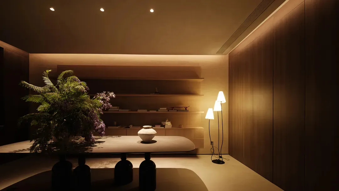 Modern dining room featuring a dark wooden dining table with rattan chairs, a pendant light, and a plant in a vase.