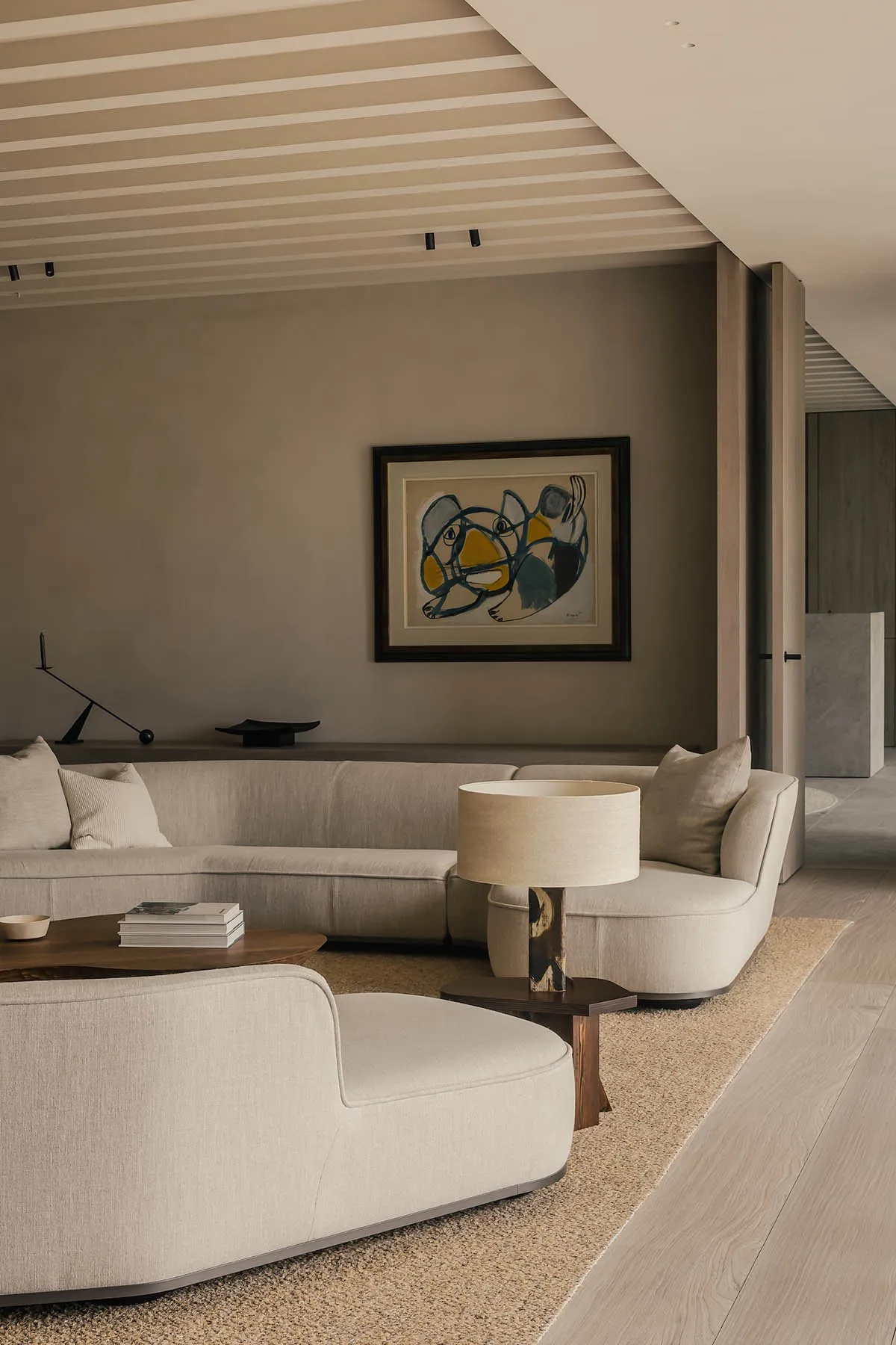 Modern living room featuring an orange armchair, neutral-toned sofa, and abstract wall art.