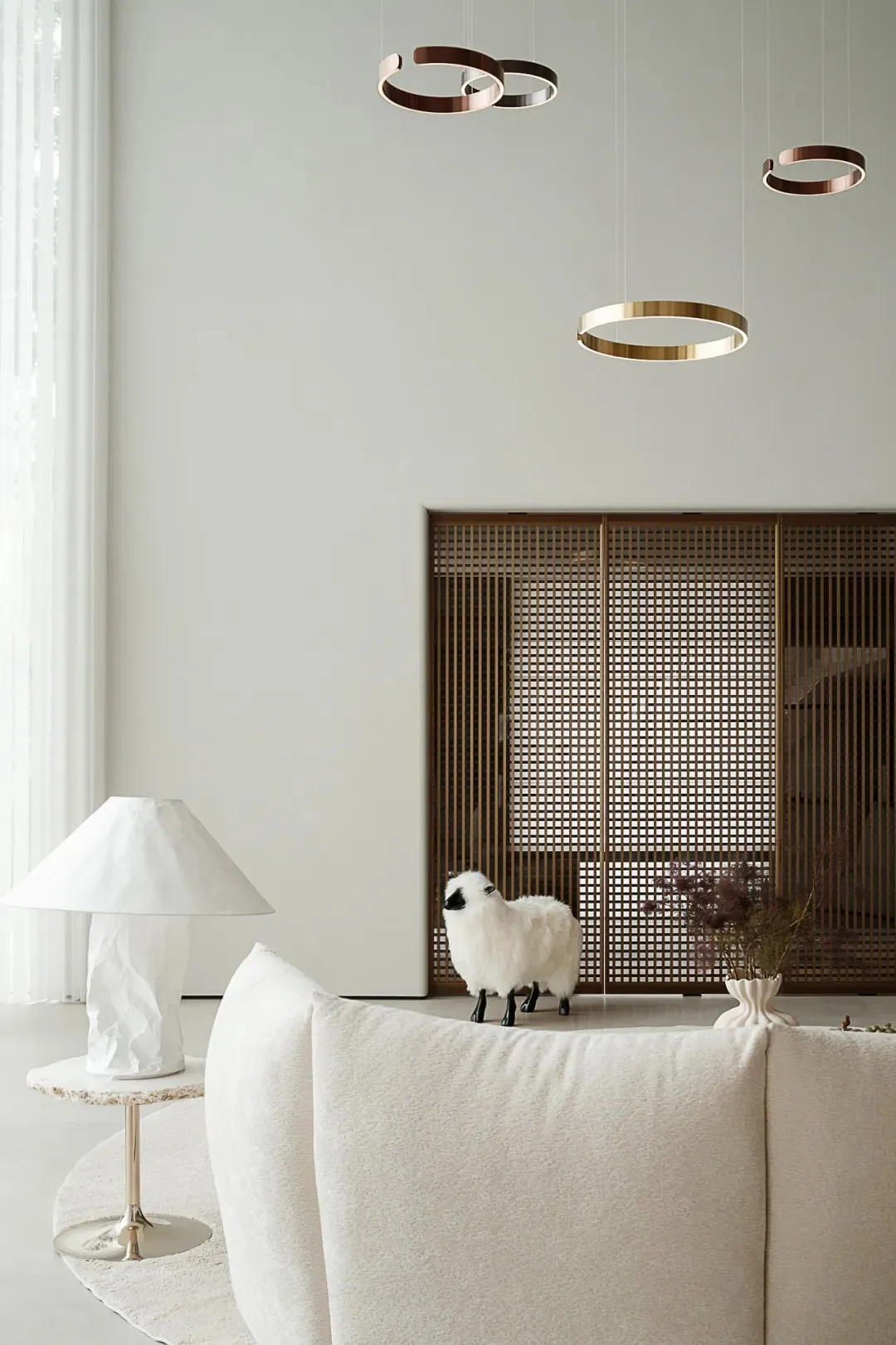 Modern minimalist living room featuring a white sofa, a white table lamp, and a metal decorative wall panel.