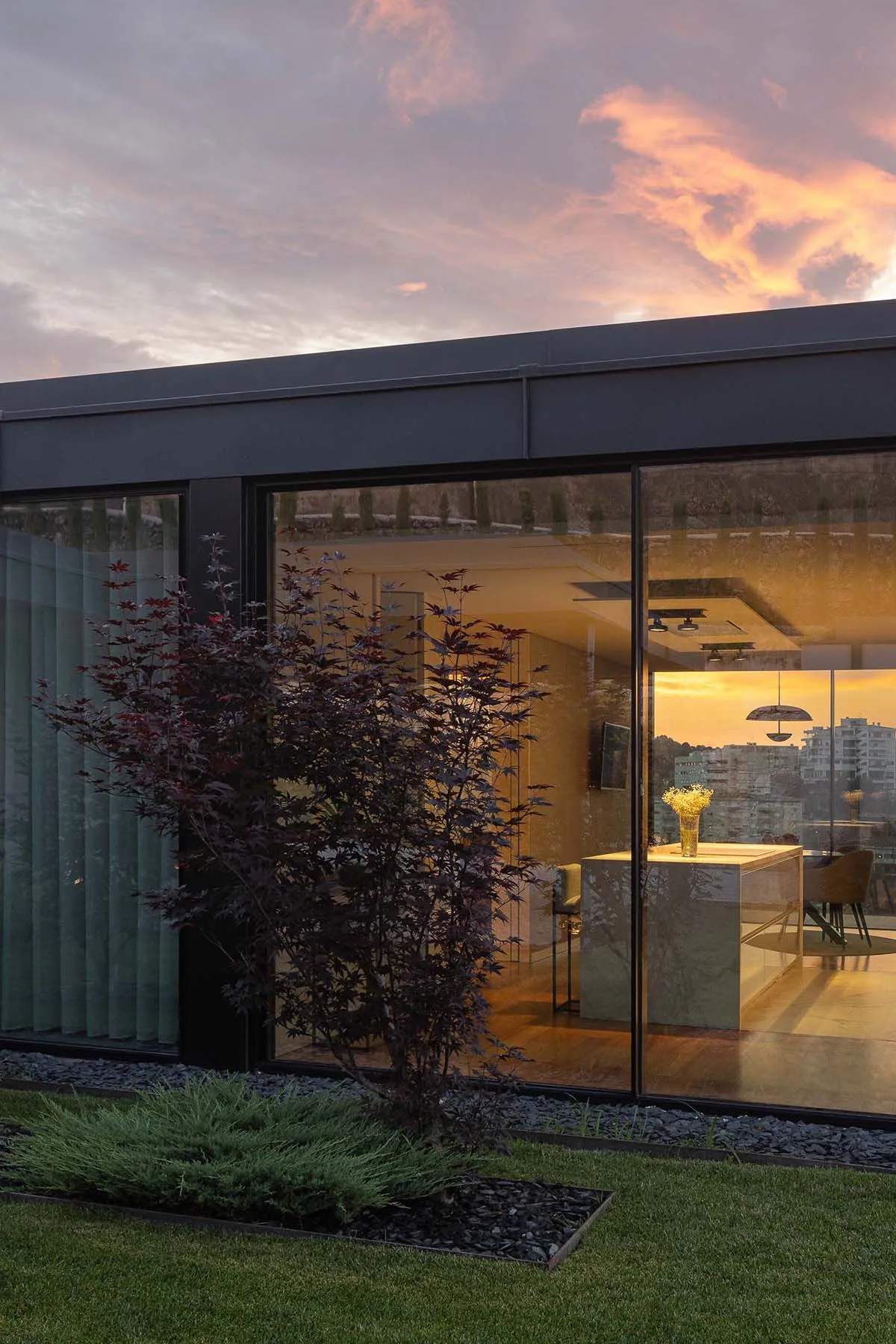 A minimalist house exterior featuring large glass windows and a modern design.