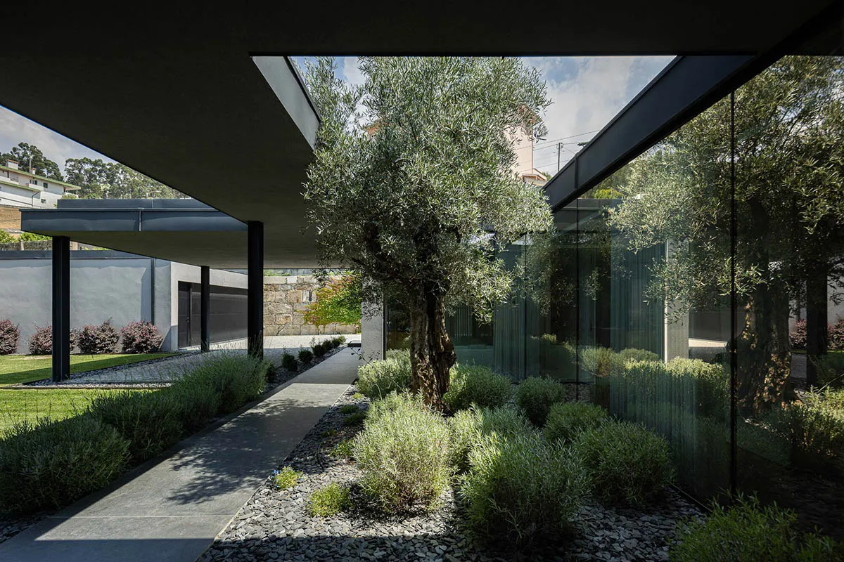 Modern house exterior featuring glass walls and concrete structures.