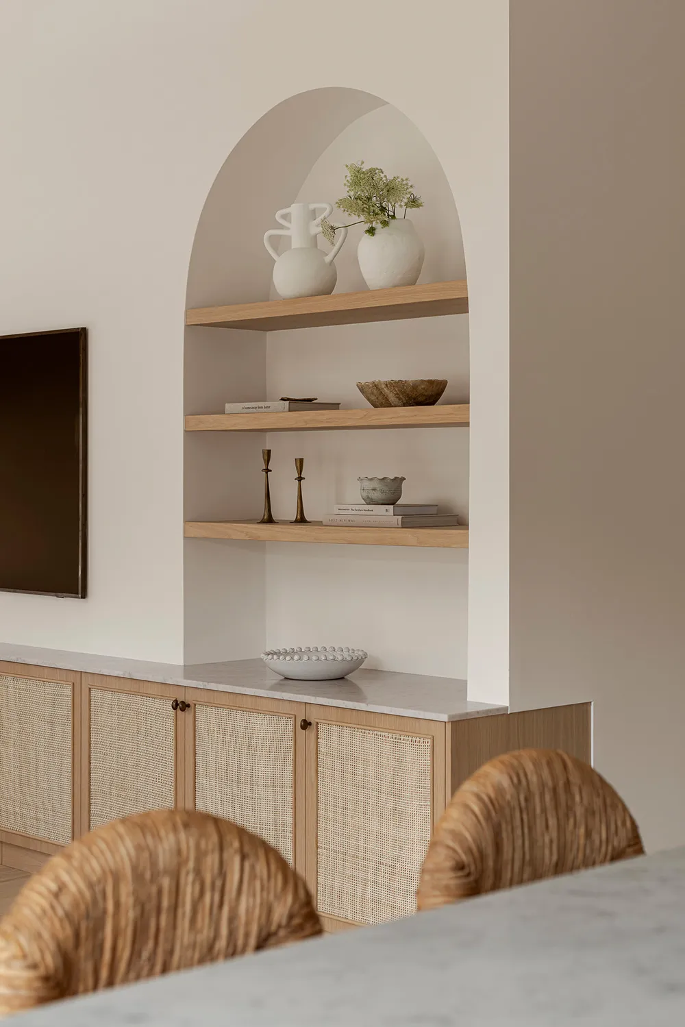 A modern kitchen featuring marble countertops and timber cabinets with woven accents.