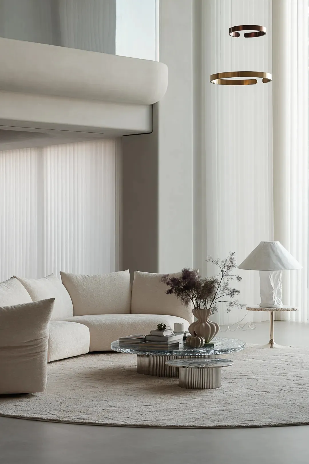 A modern living room featuring a curved sofa upholstered in neutral-toned leather, a round marble side table, and a hanging b