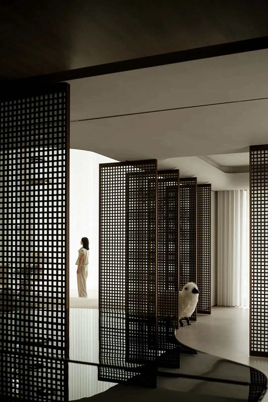 Modern minimalist hallway with black metal mesh panels and white curtains.