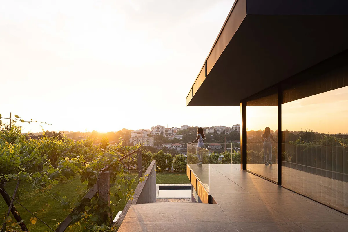 A modern house featuring concrete and glass materials with a scenic rooftop view.