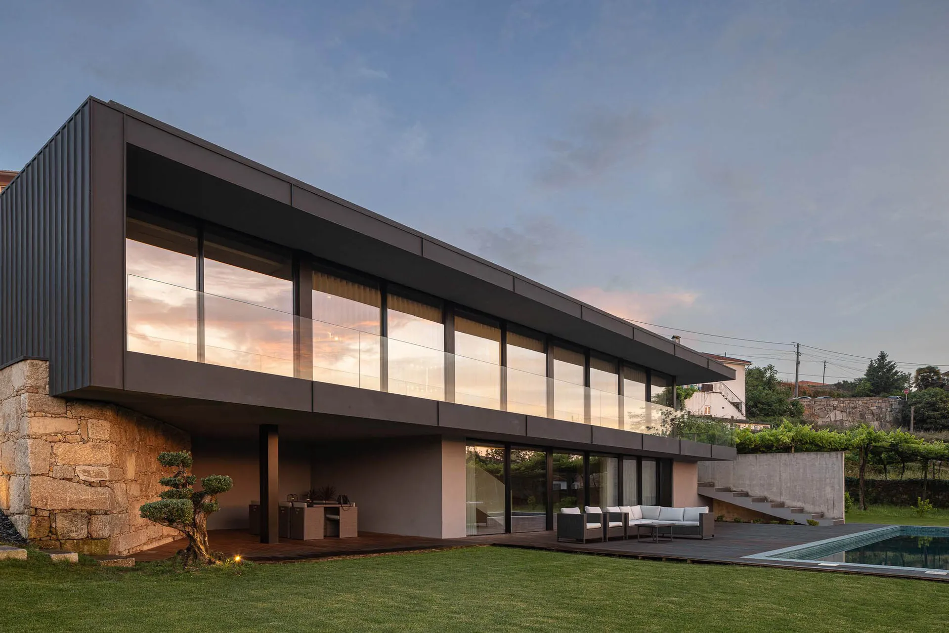 Modern residential house featuring a glass facade and concrete elements, viewed from the exterior.