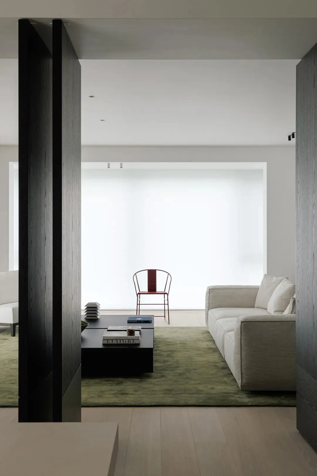 A modern living room featuring a white sofa on a green carpet with wooden panels and a minimalist design.