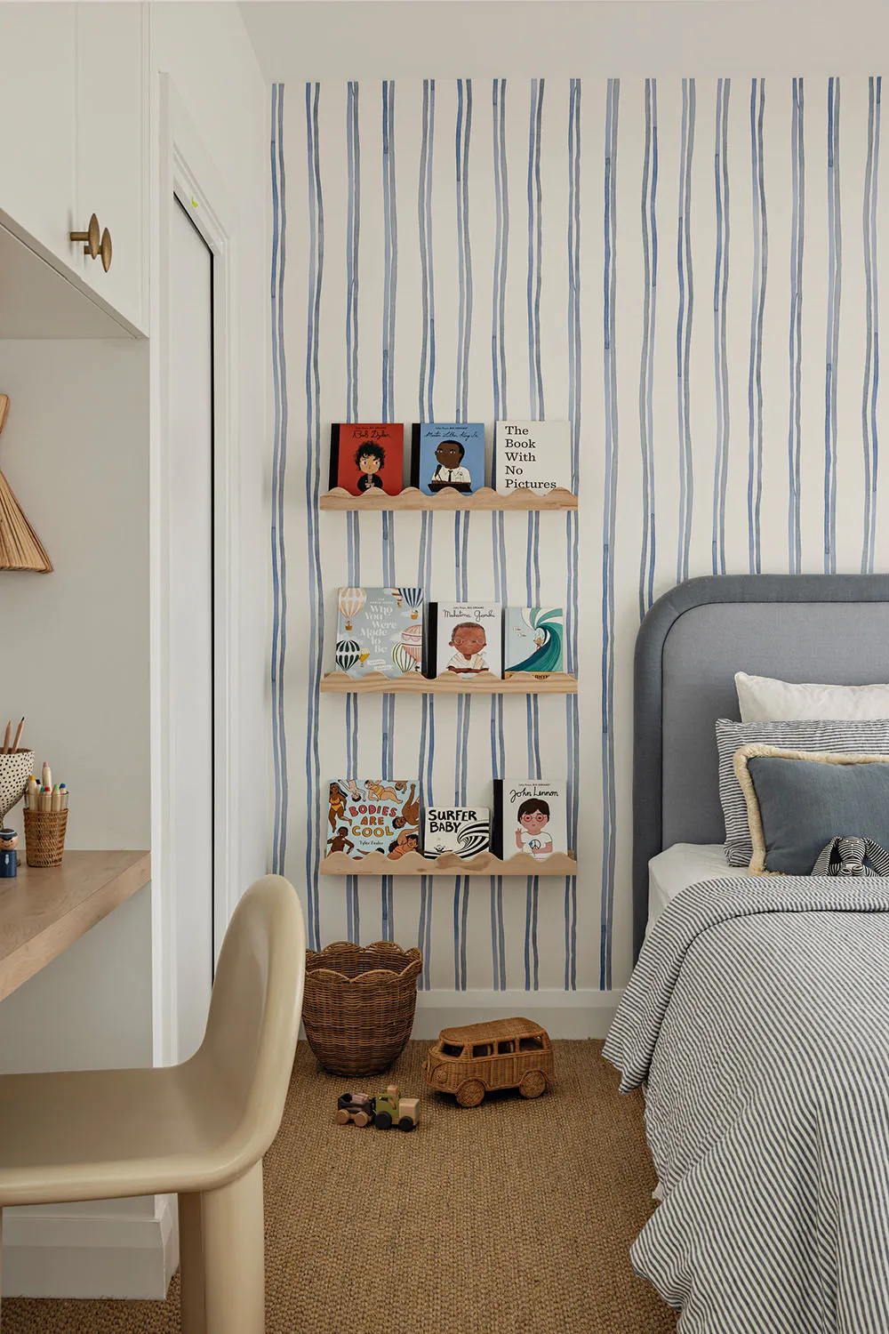 A modern bedroom featuring striped wallpaper, wooden shelves, and a green chair.