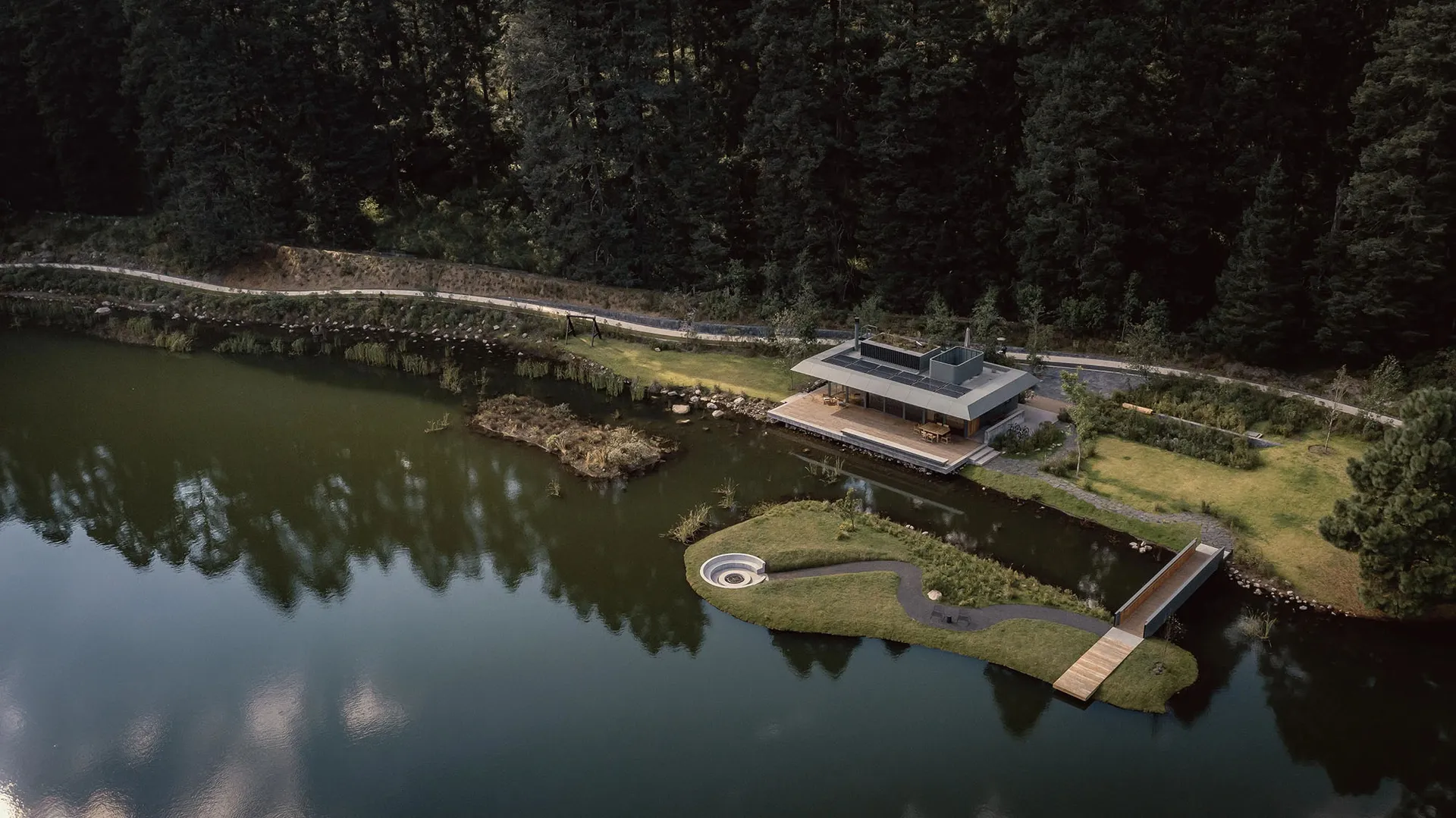 A modern waterfront house featuring concrete, glass, and wood materials.