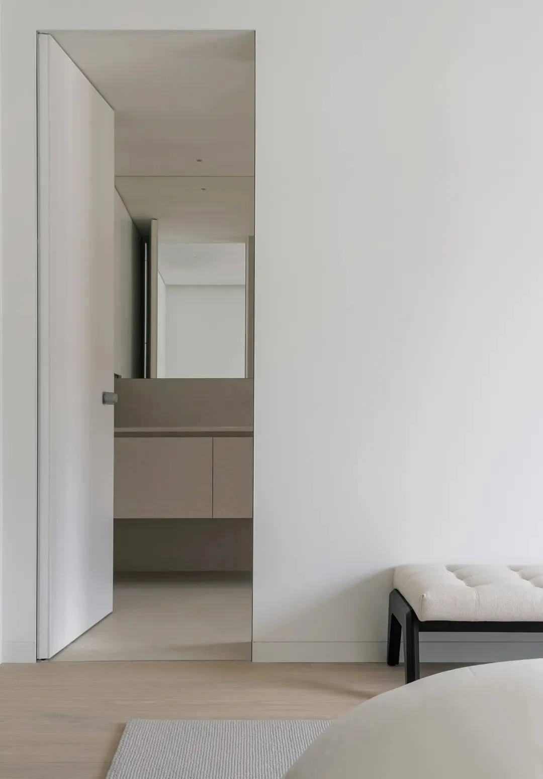 Modern minimalist white bedroom suite with neutral tones, clear glass shower enclosure, white bedding, and sleek black accent