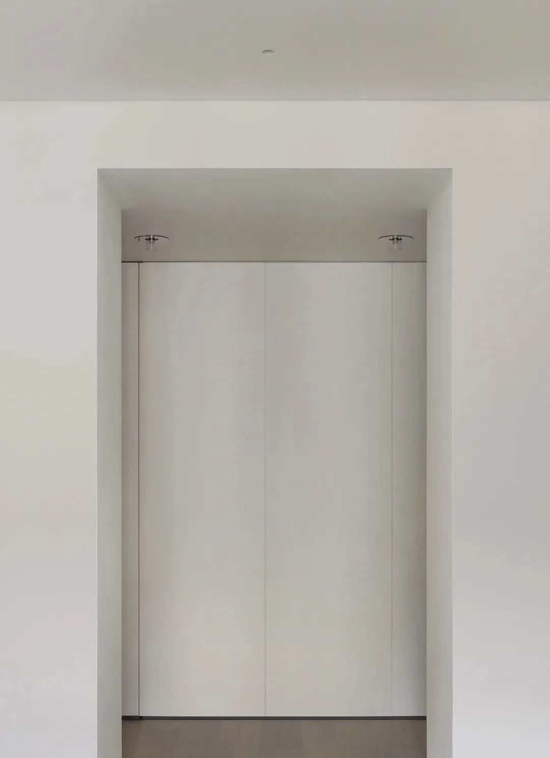Modern minimalist entryway with white paneled walls and minimalist lighting fixtures.