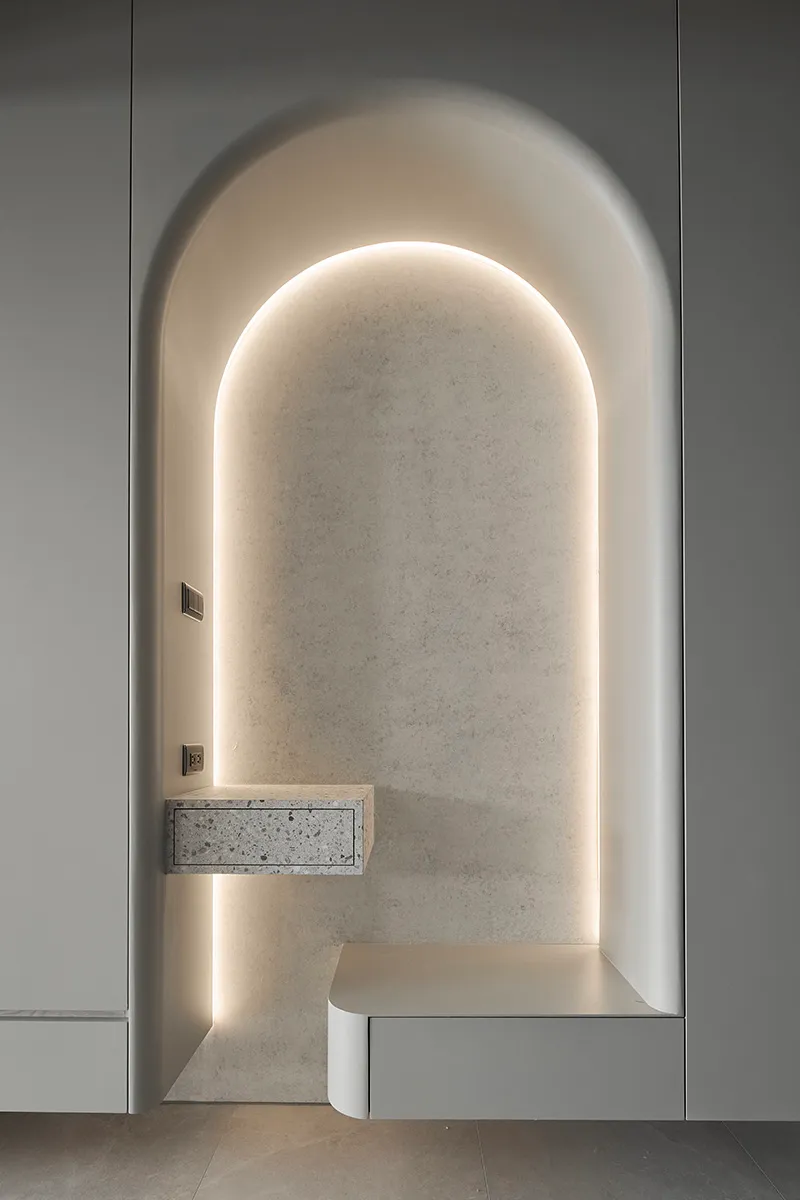 A minimalistic, modern design with an arched recessed alcove lined with terrazzo and lighted by concealed lighting.