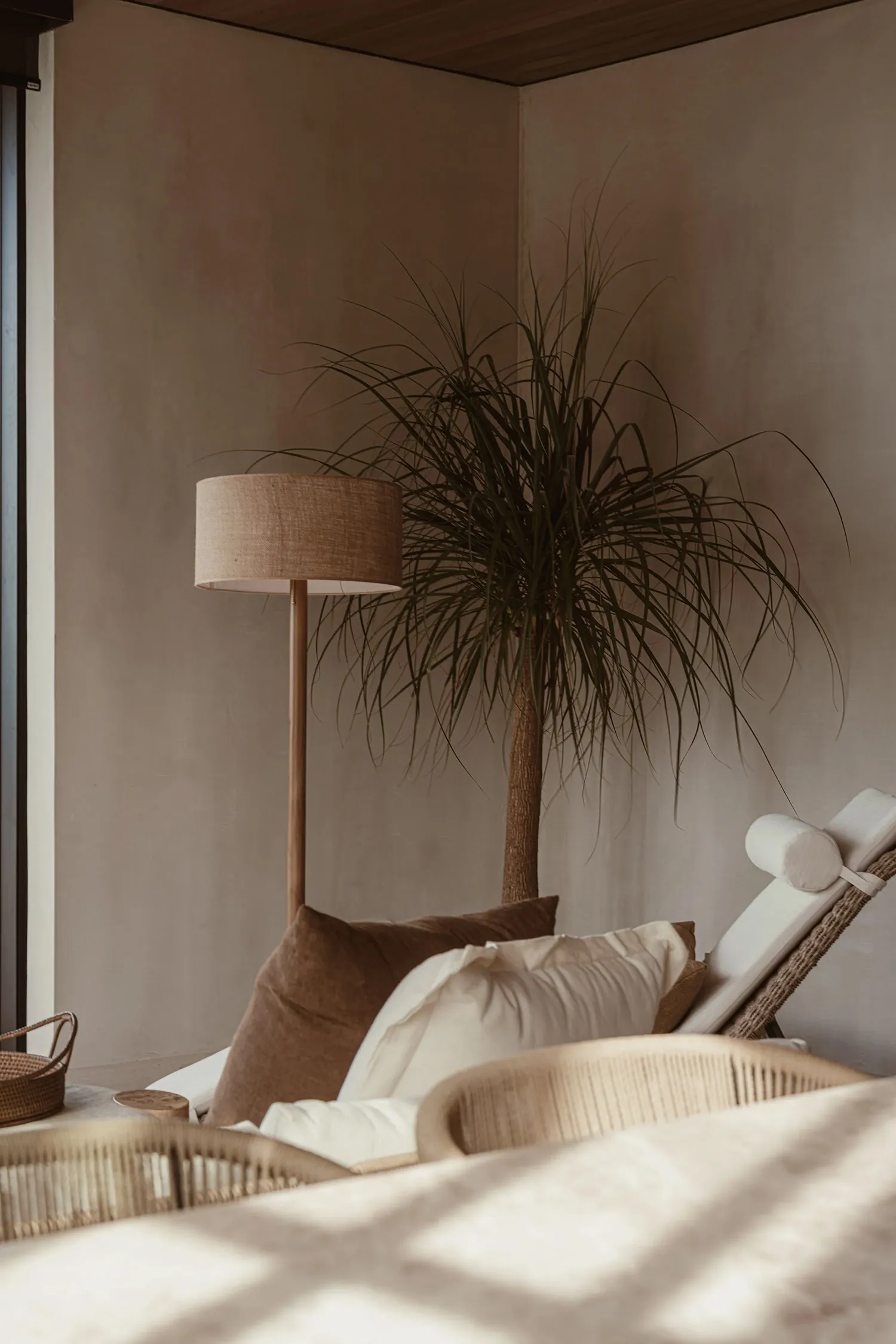 Modern minimalist living room featuring rattan furniture, linen cushions, and wooden blinds.