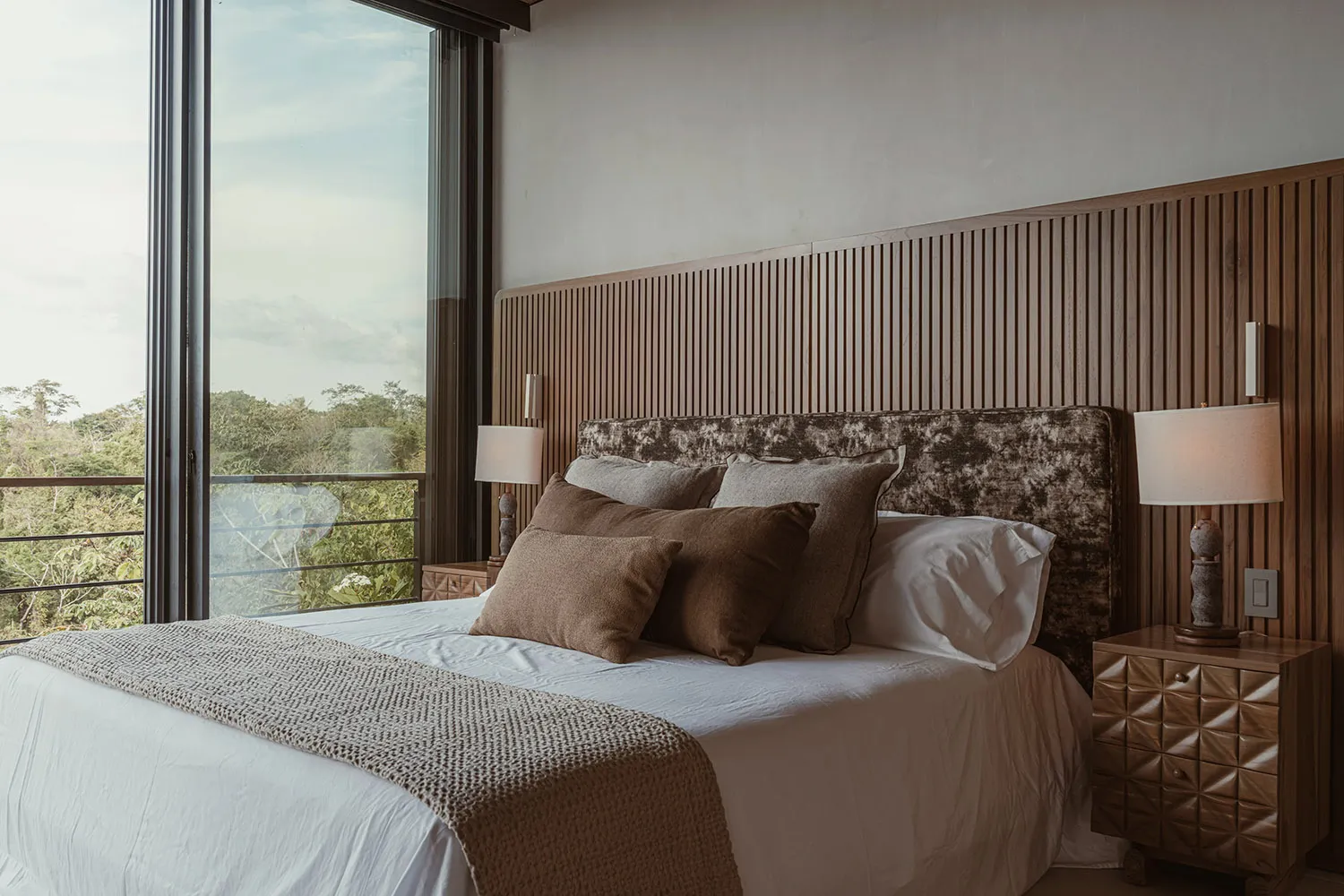 Modern bedroom featuring a wooden headboard and white bedding with brown decorative pillows.