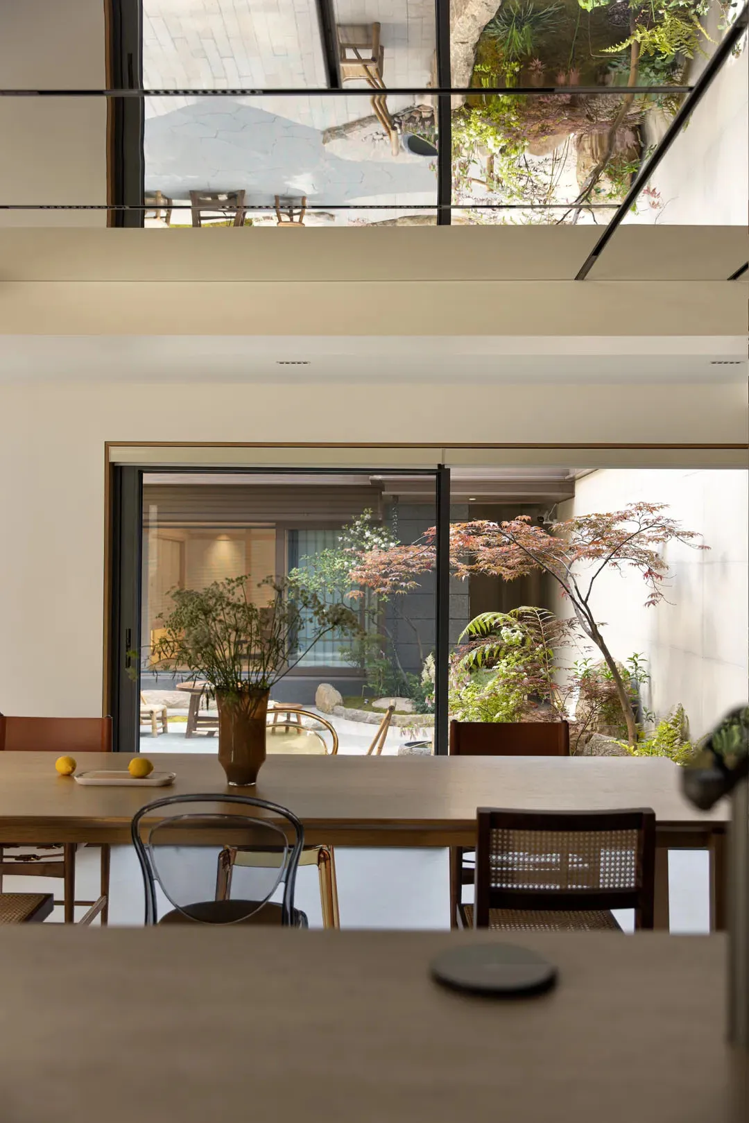 A modern dining room featuring wooden furniture and a serene outdoor view.