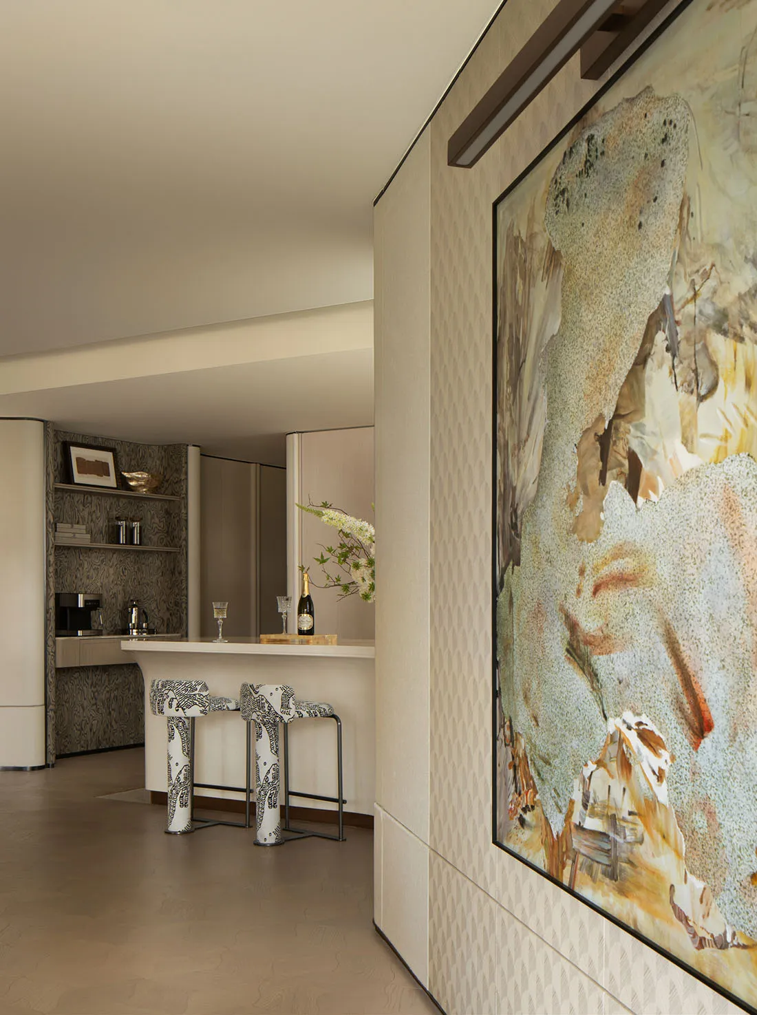 A modern kitchen bar with two stools, tiled flooring, and a framed abstract painting.