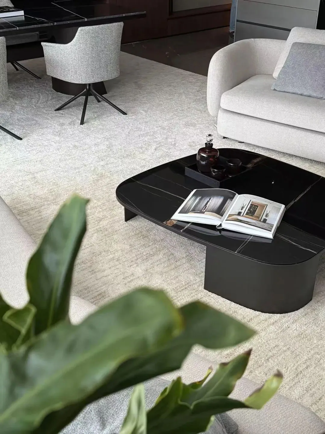 Modern living room with a black marble coffee table, white couch, and grey chairs.