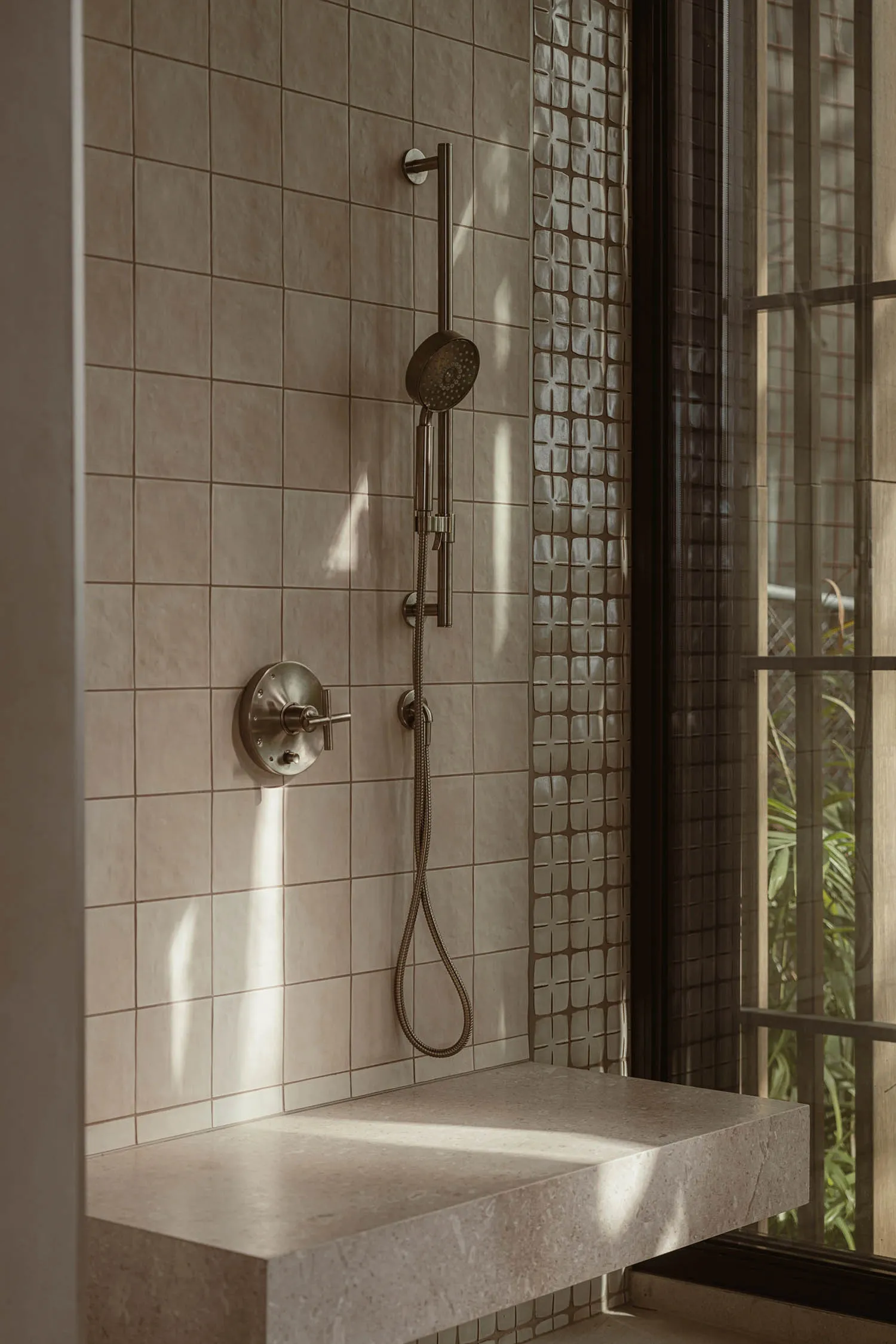 A modern bathroom with a tile shower featuring a handheld showerhead, overhead shower, and floating vanity.