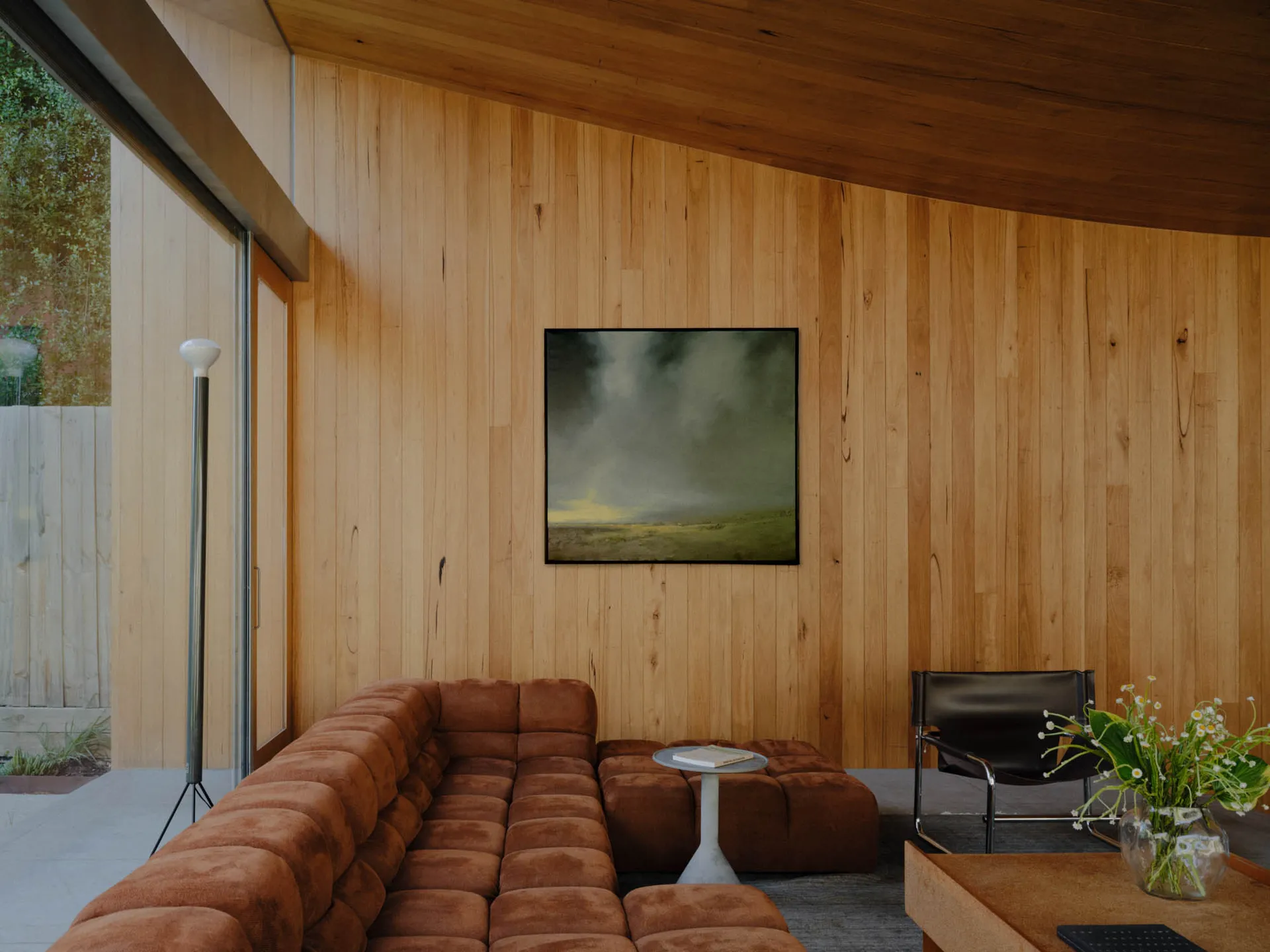 A modern living room with wooden walls and a plush brown sofa.