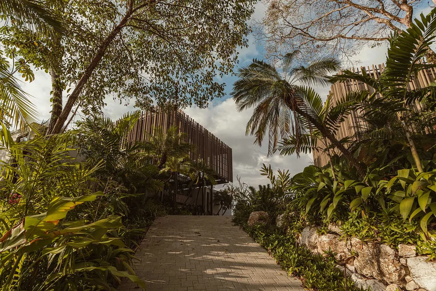 A modern landscape featuring natural elements and a pathway leading through a lush, green environment.