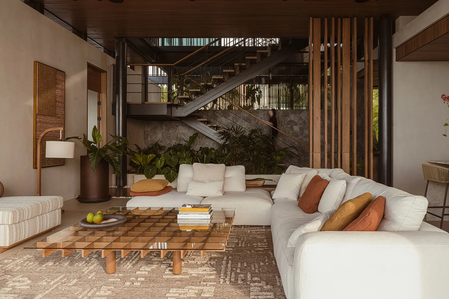 A modern living room with neutral-toned furniture and decor, featuring a cozy sectional, a glass coffee table, and various in