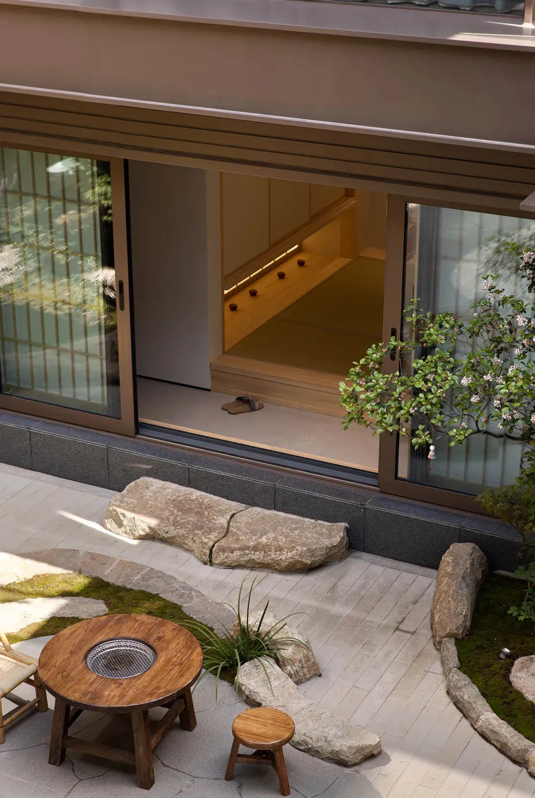 A traditional Japanese entrance way featuring natural stone, wood, and glass materials.
