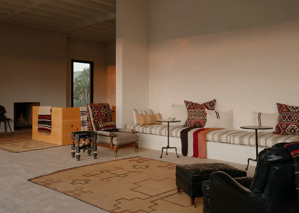 A minimalist living room with a low-slung couch adorned with patterned cushions and throw blankets, accompanied by a wooden t