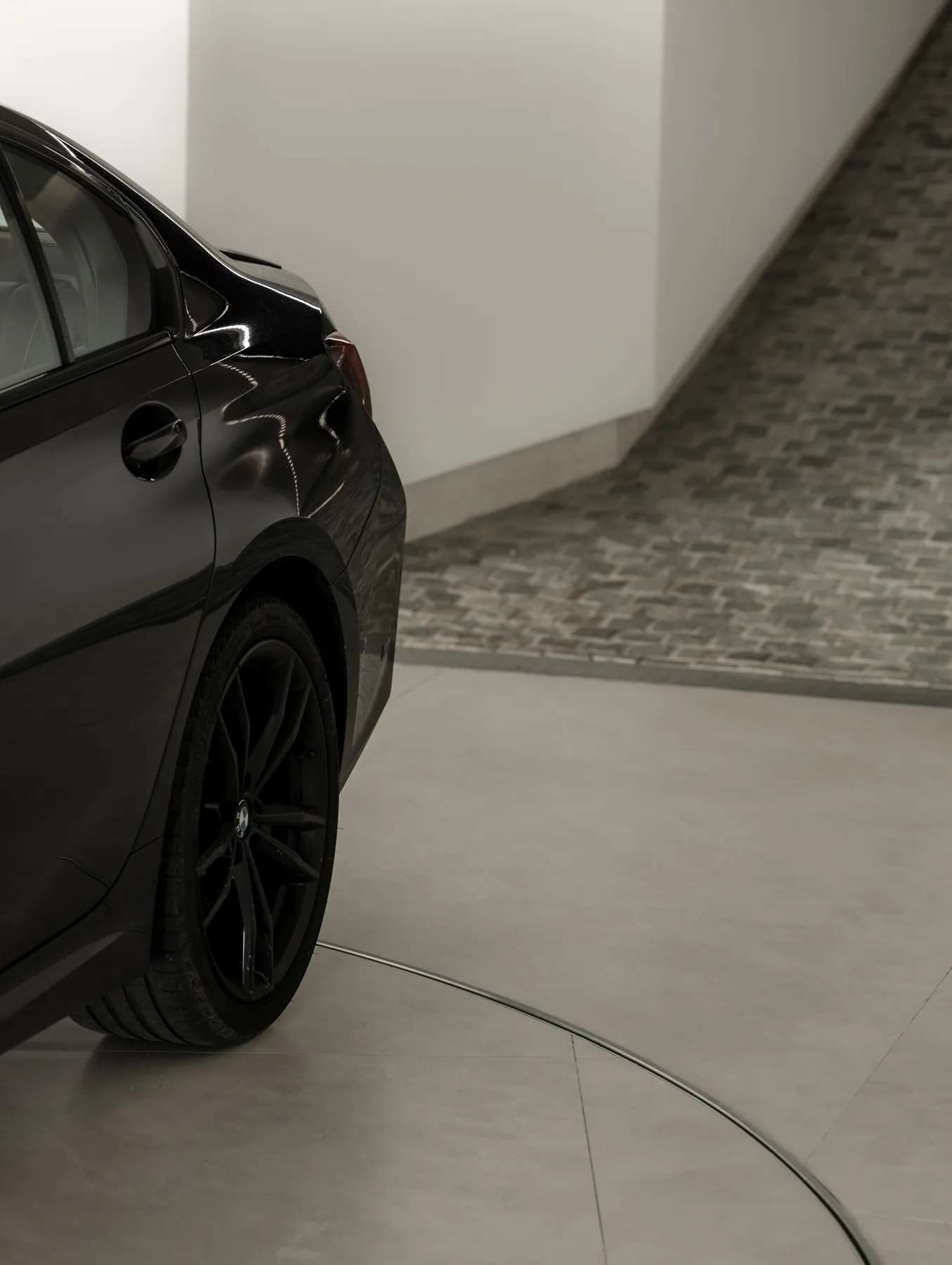 A modern black car parked in a concrete interior