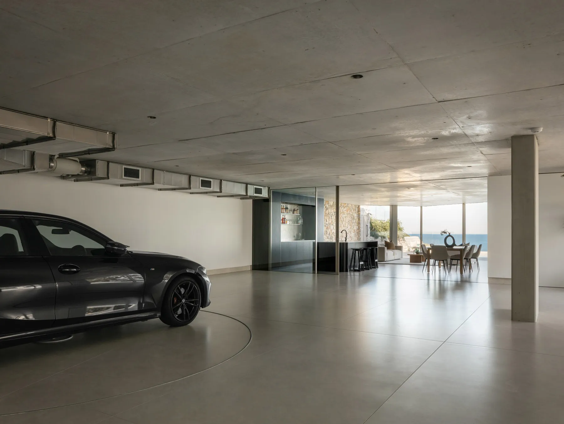 A sleek, modern garage interior with a black vehicle parked in a concrete floor room.