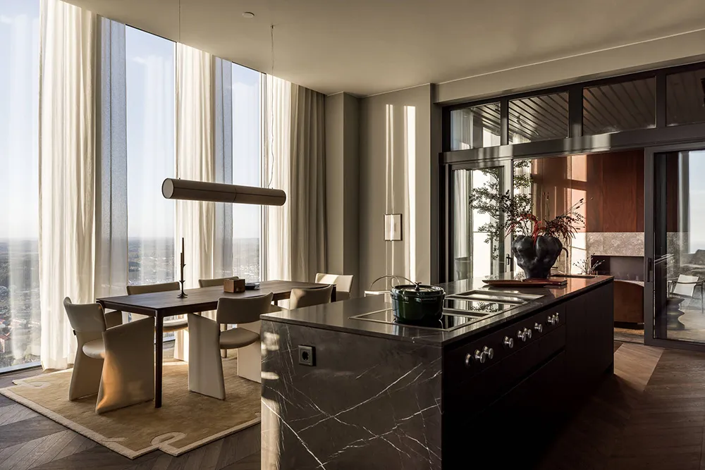 Modern minimalist kitchen featuring marble countertops and floor-to-ceiling windows.