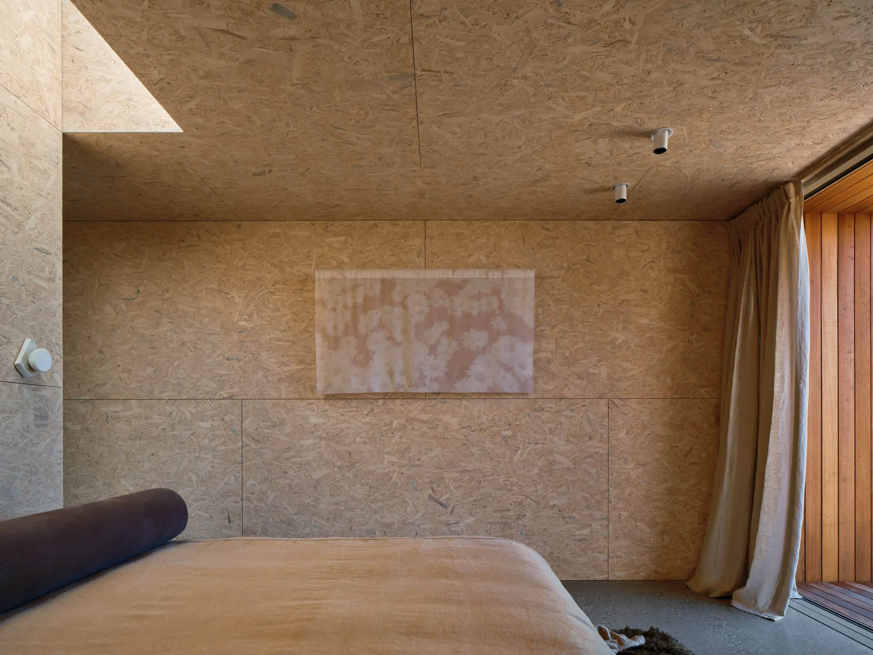 Minimalist bedroom with a bed and OSB board wall