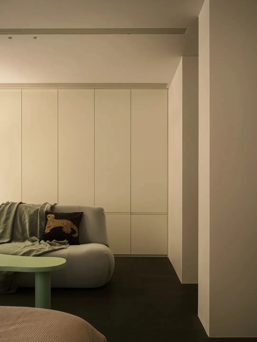 Minimalist living room with a white sofa, green coffee table, and stylish light fixture.