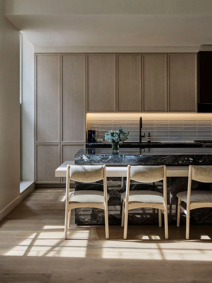 A modern minimalist kitchen with marble countertops and white oak cabinets.
