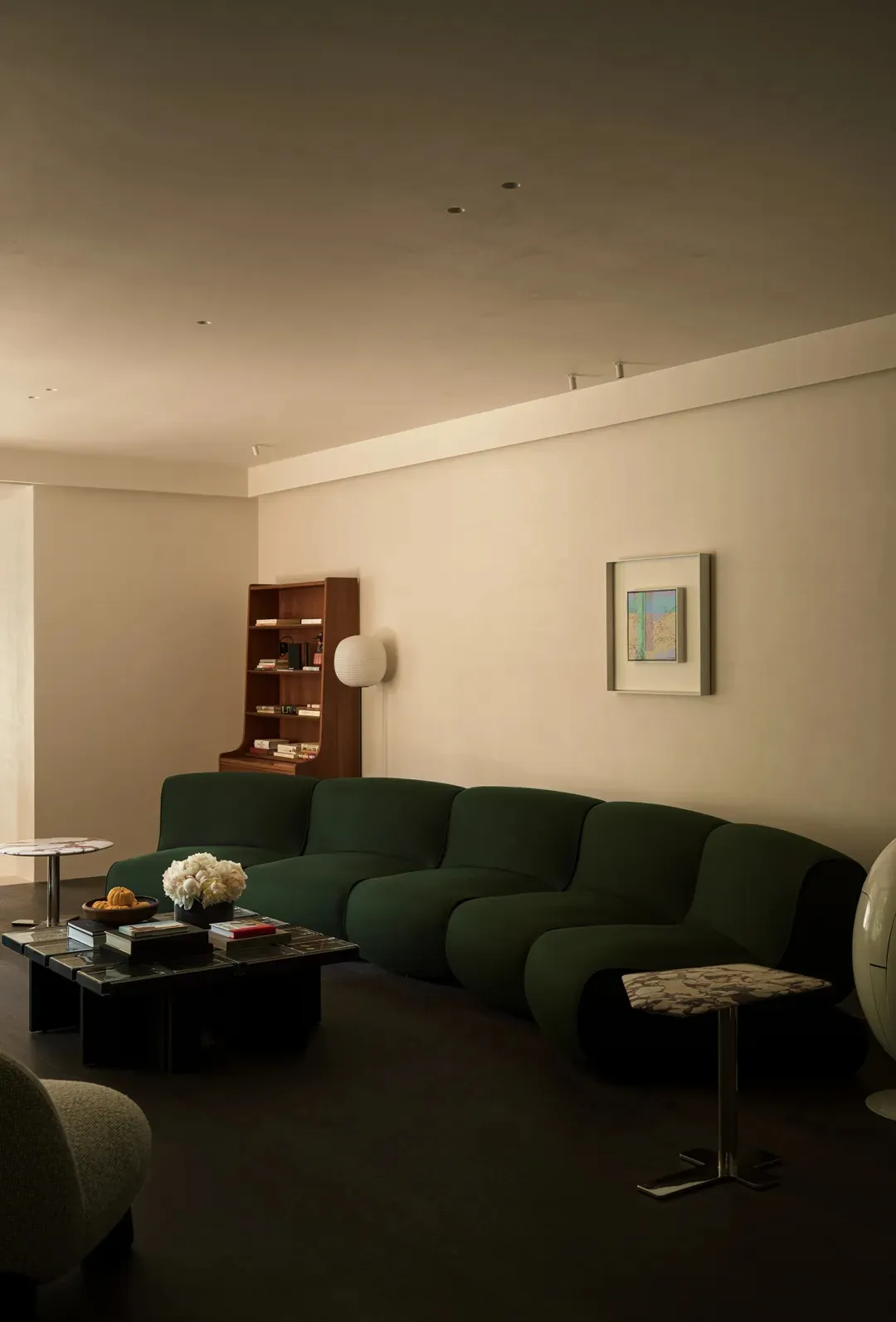 A modern living room featuring a green modular sofa, a round side table, and bookshelf.