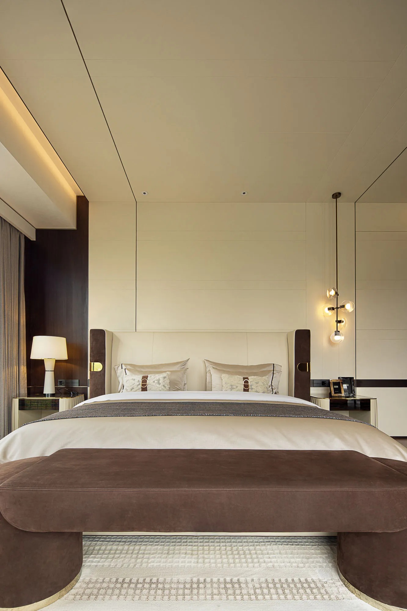 Modern minimalist bedroom featuring a bed with white and beige textiles and a brown upholstered bench.