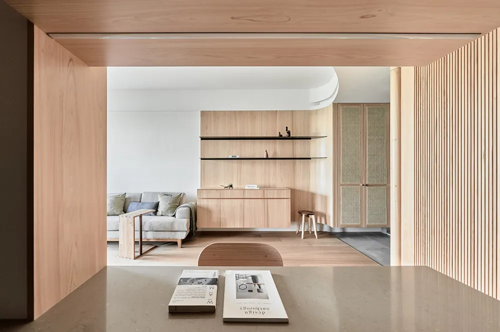 A minimalist living room featuring wood furniture and shelves.