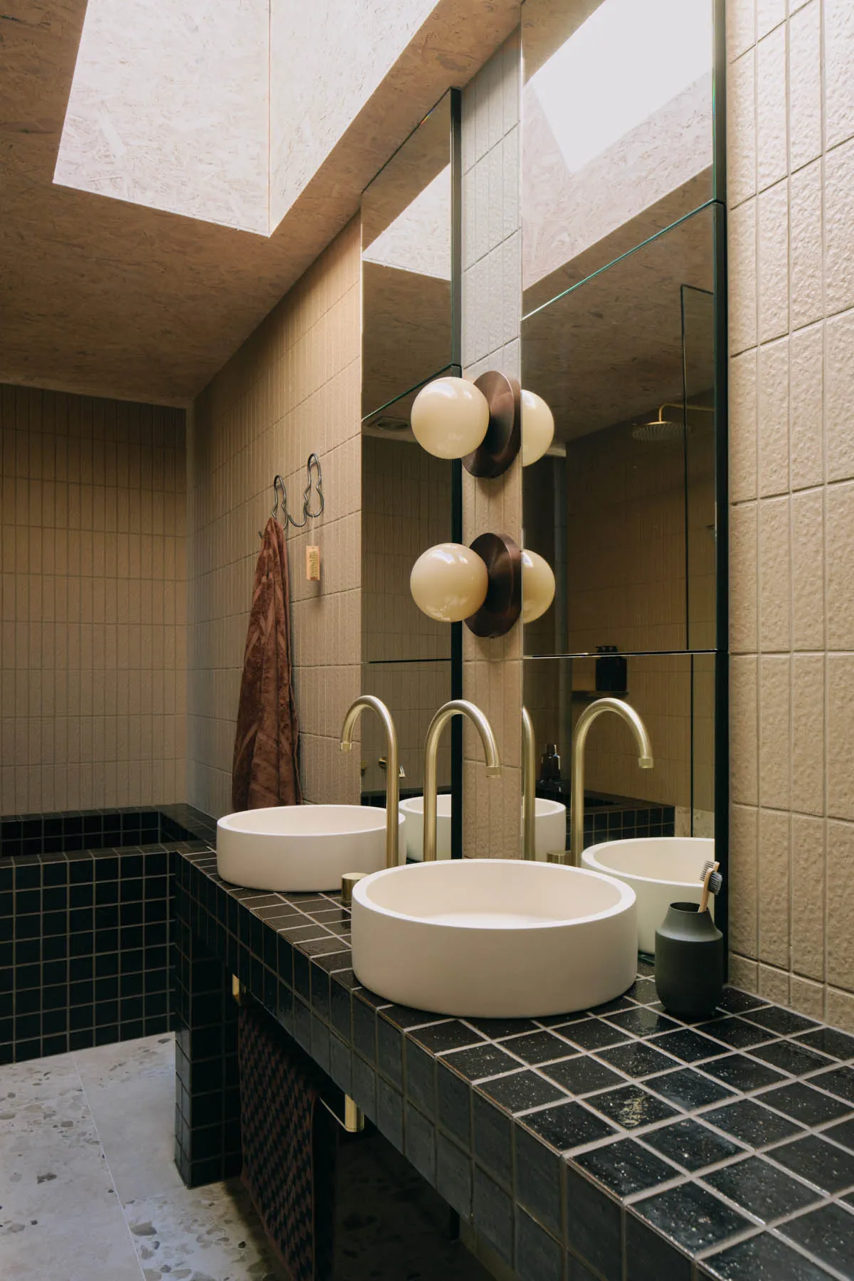 Modern bathroom featuring black and white tiled walls, a black countertop, and a white ceramic sink with a round bowl shape.