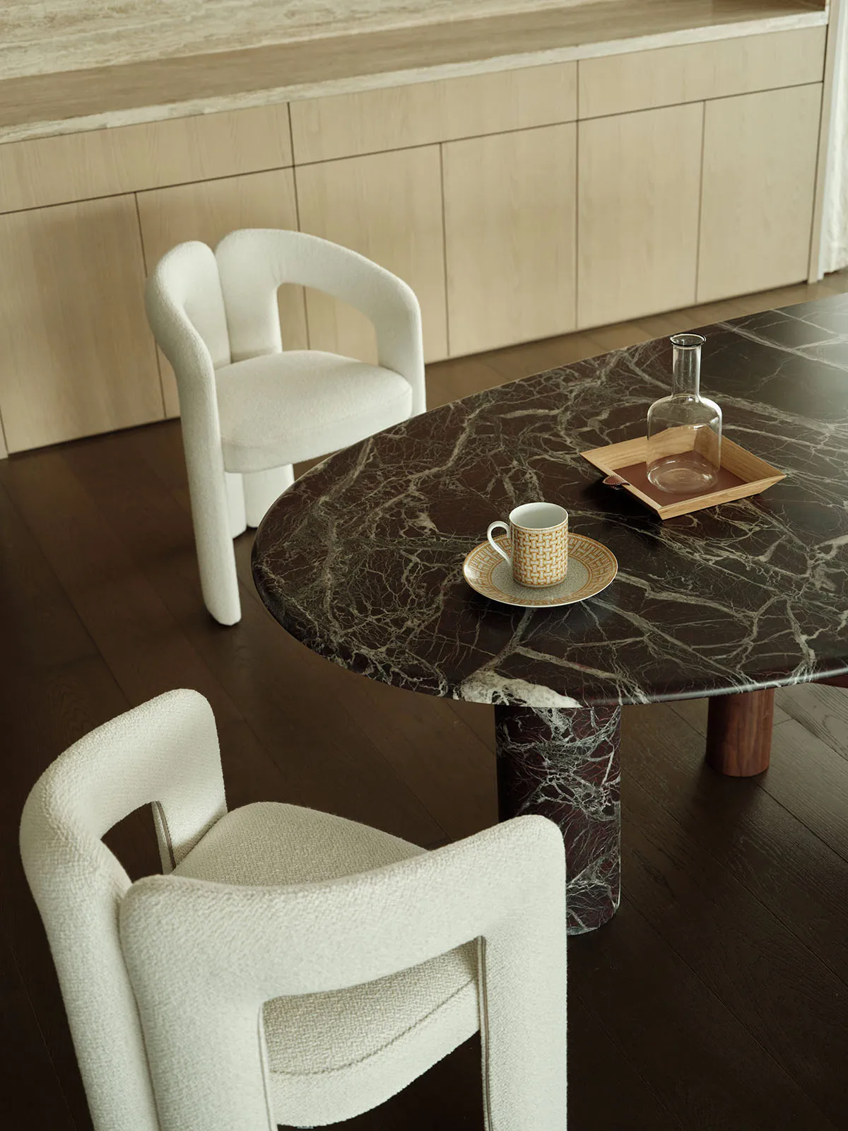 Modern dining room with marble table and white upholstered chairs.