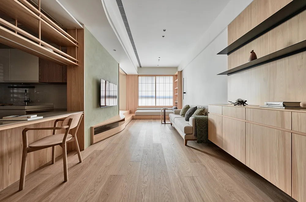 A modern living room with wooden furniture, including a white sofa with green cushions, a built-in entertainment center, and