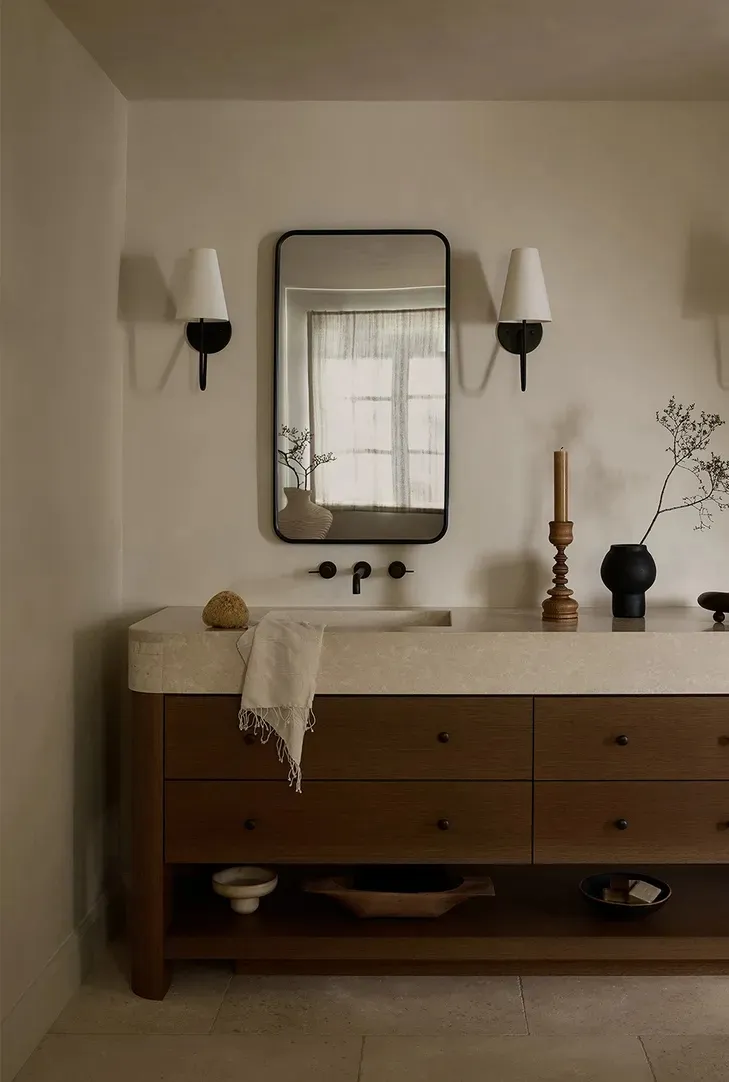 A modern minimalist bathroom with a stone countertop and wooden drawers.