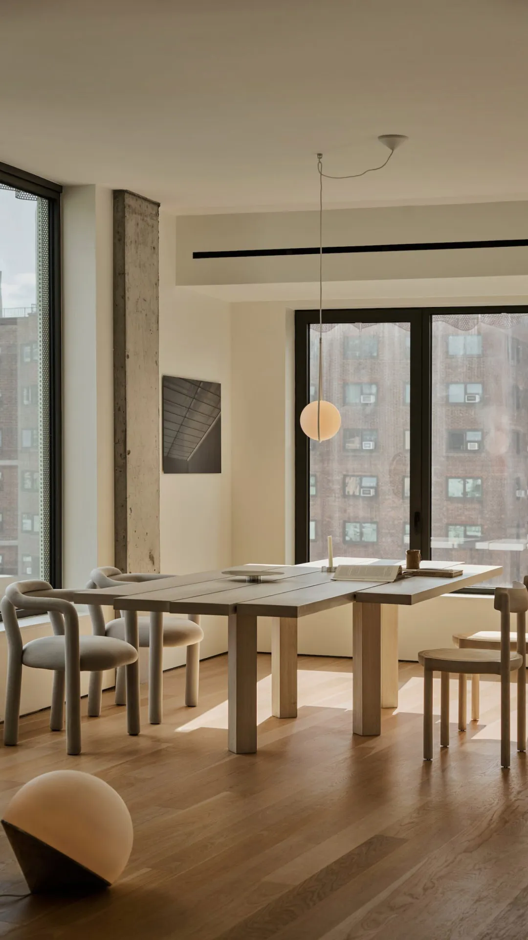 Modern dining room featuring a wooden table, minimalist chairs, and a spherical pendant light.