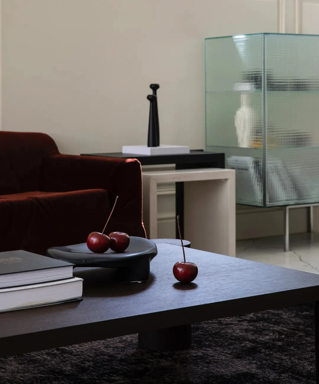 Modern living room with wooden coffee table, red cherries, dark furniture, and glass cabinet.