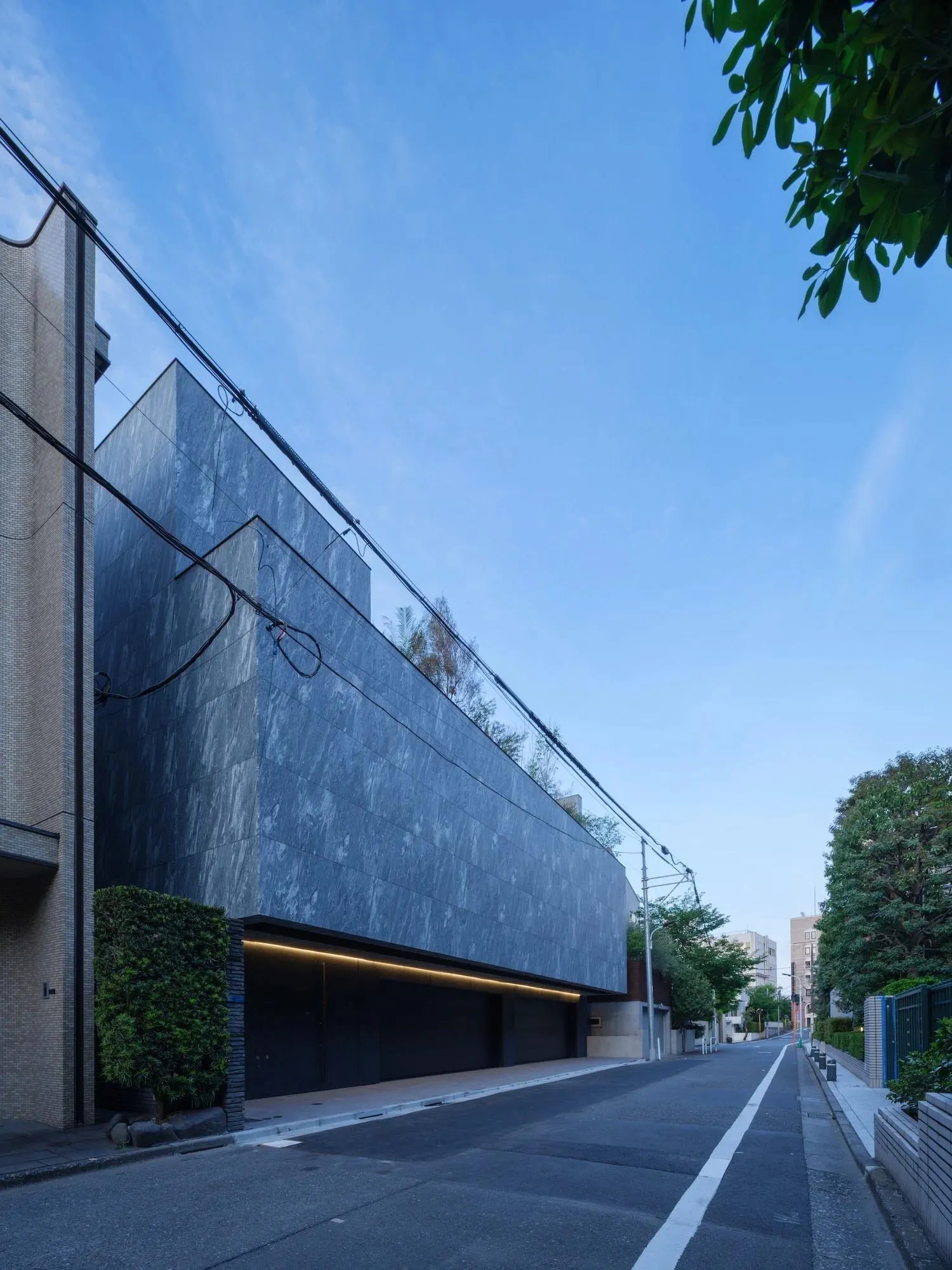 A modern building exterior made of dark grey, textured concrete.