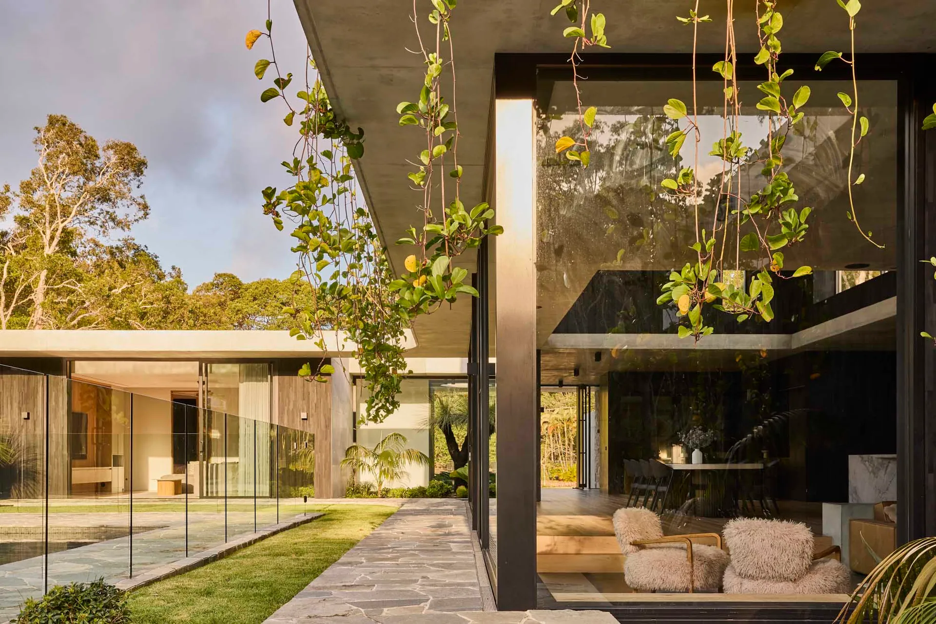 Modern residential interior with concrete and glass elements, featuring tranquil outdoor space.