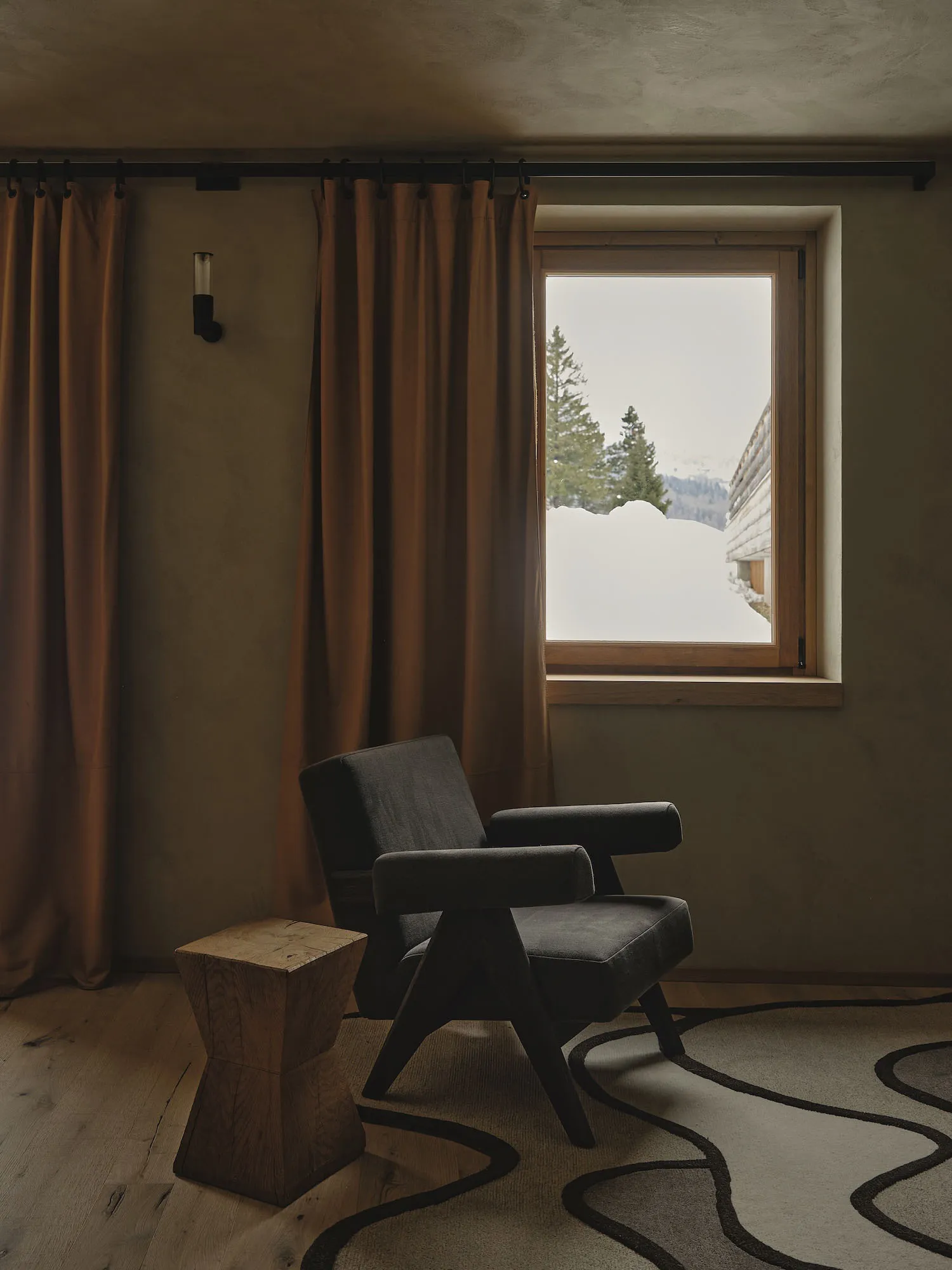 A modern living room with wooden furniture and a cloth seat, featuring a window with a view of snow-covered mountains.