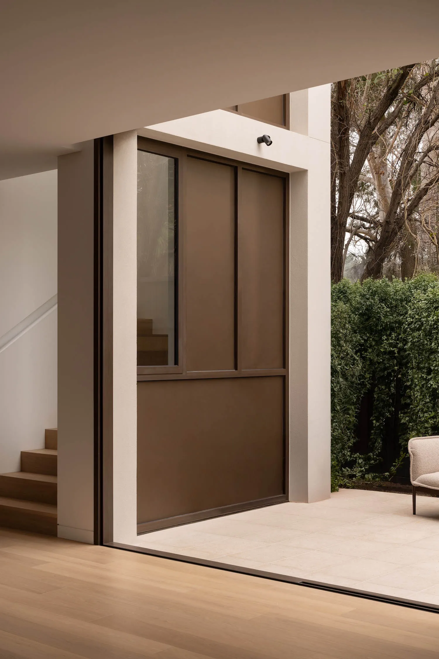 Modern home entryway with black metallic door and tiled flooring, featuring a minimalist design style.