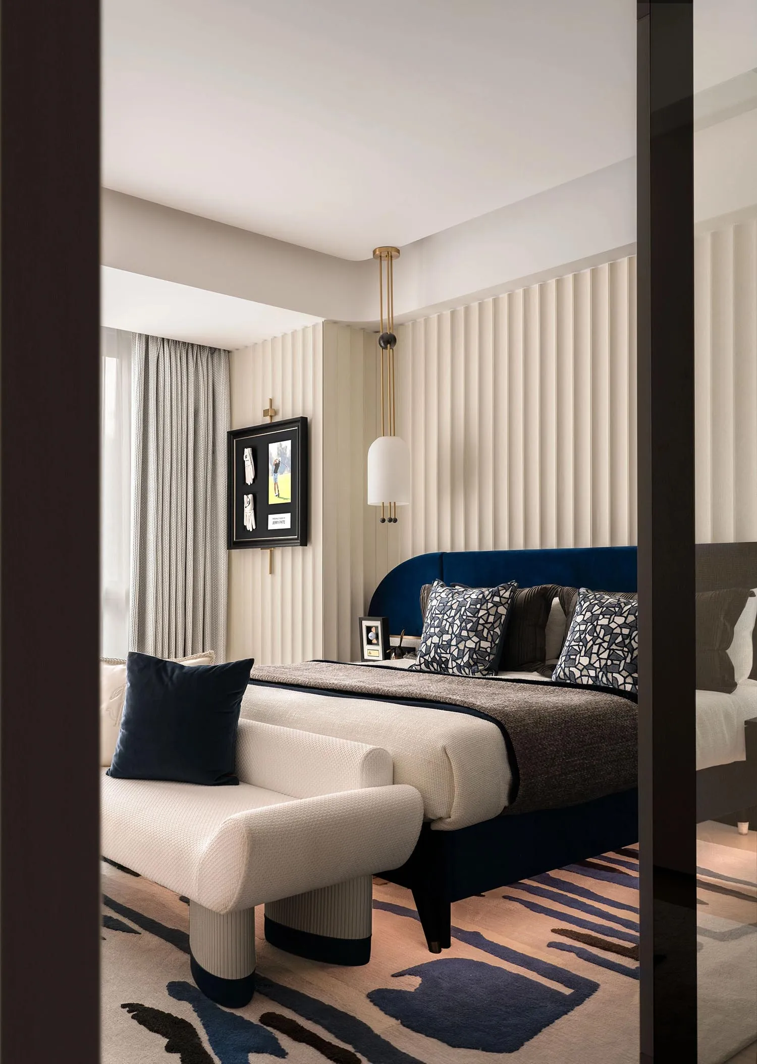 A modern bedroom featuring a fabric upholstered bed and geometric patterned rug.