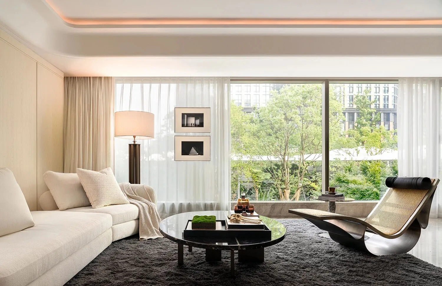 Modern, minimalist living room with white sofa, metal chair, and glass coffee table.