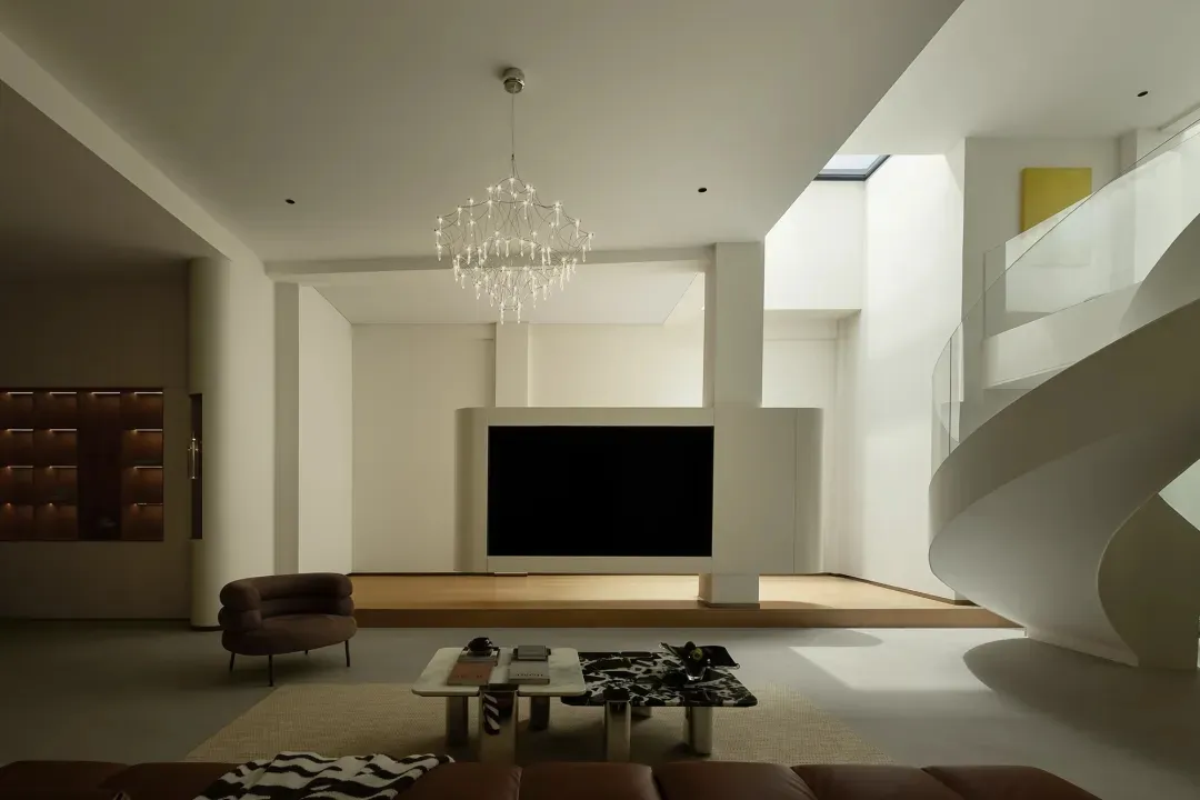 A contemporary minimalist living room with a large light fixture, a sleek sofa, and a modern coffee table.