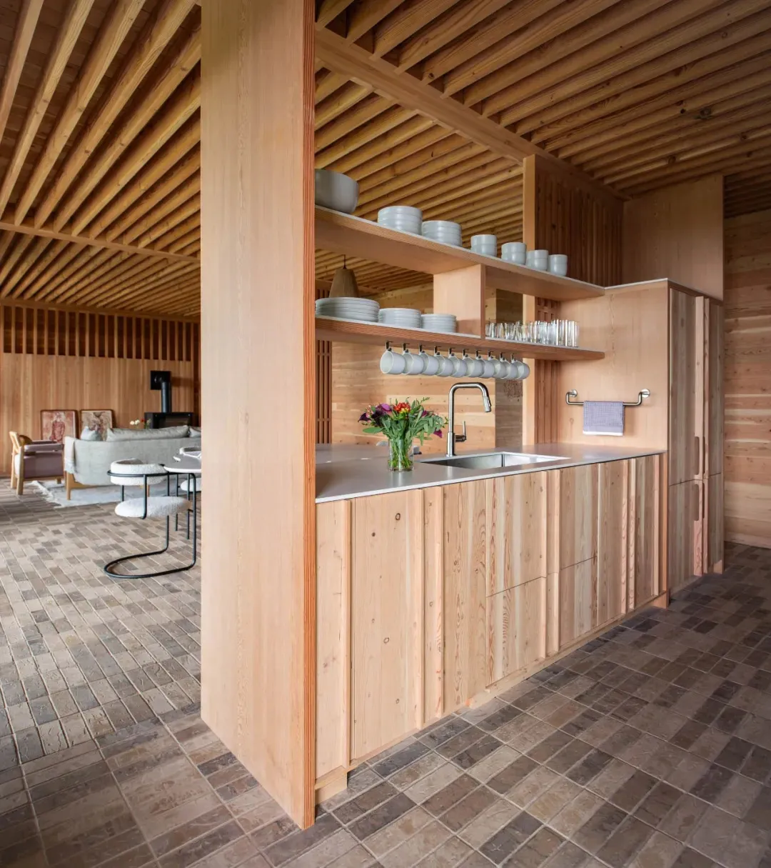 Modern minimalist kitchen with wooden cabinets, stainless steel countertops, and open shelving